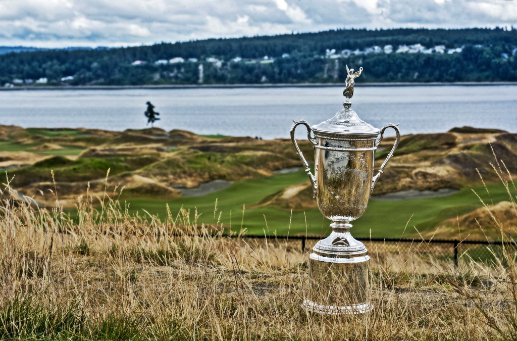 US Open trophy on grassy field against golf course backdrop