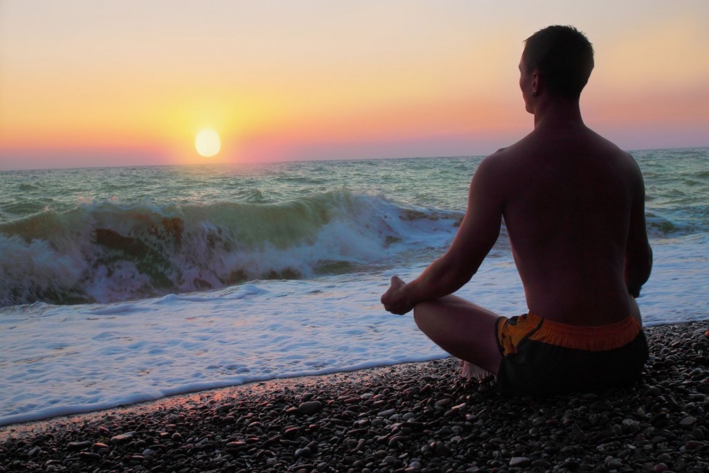 Man meditating on the shore of the sea