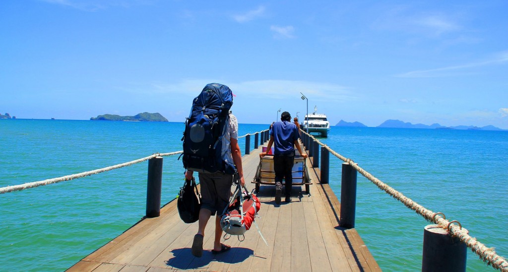 backpackers walking along pier against ocean backdrop